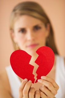 Young woman holding broken paper heart. Photo: Daniel Grill