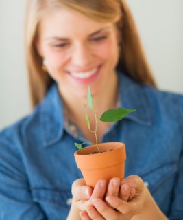 Young woman holding small plant. Photo : Daniel Grill