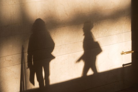 Shadow of two female pedestrians on sunlit wall. Photo : fotog
