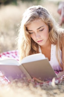 Teenage girl (16-17) reading book outdoors. Photo : Take A Pix Media