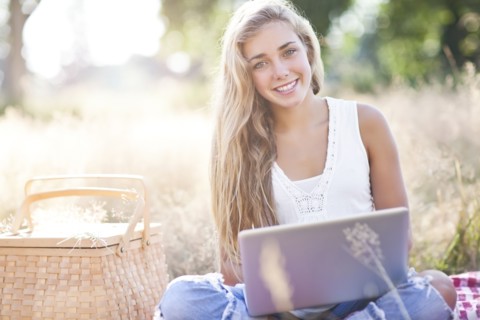 Teenage girl (16-17) posing with laptop outdoors. Photo : Take A Pix Media