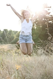 Happy teenage girl (16-17) jumping in bright sunshine. Photo : Take A Pix Media