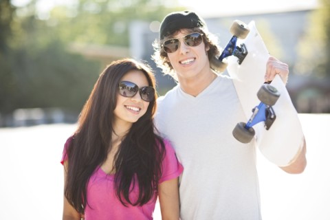 Young multi-racial couple posing with skateboard. Photo : Take A Pix Media