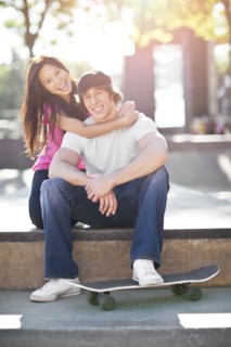 Young multi-racial couple posing with skateboard. Photo : Take A Pix Media