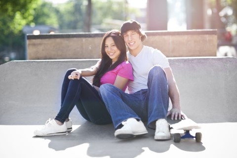 Young multi-racial couple posing with skateboard. Photo : Take A Pix Media