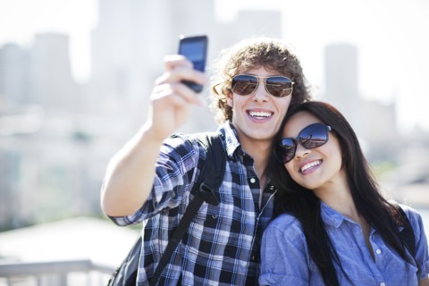 USA, Washington, Seattle, Couple wearing sunglasses photographing themselves with smart phone.