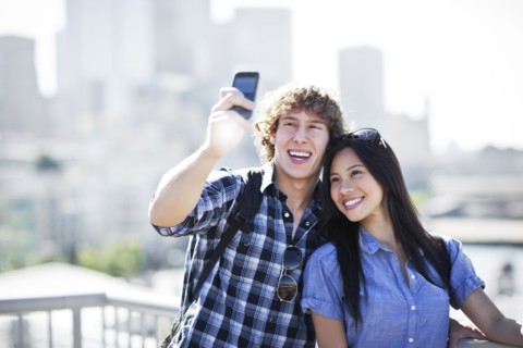 USA, Washington, Seattle, Couple wearing sunglasses photographing themselves with smart phone.