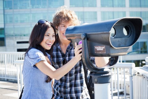 USA, Washington, Seattle, Couple looking through coin-operated binoculars. Photo: Take A Pix Media