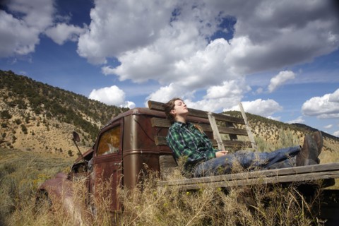 USA, Colorado, Woman resting on bed of abandoned truck in desert. Photo : John Kelly