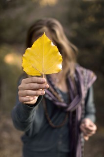 Woman holding leaf in front of face. Photo : John Kelly