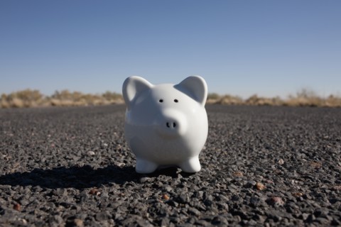 Piggy bank on asphalt road. Photo: Winslow Productions