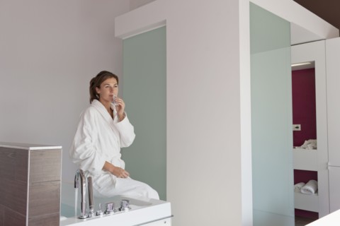 Woman in bathrobe sitting on tub. Photo : Jan Scherders