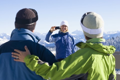 USA, Montana, Whitefish, Woman photographing friends in mountain resort. Photo : Noah Clayton