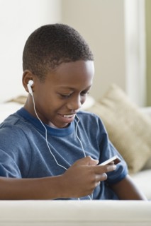 Boy (12-13) listening to music on mp3 player. Photo : Rob Lewine
