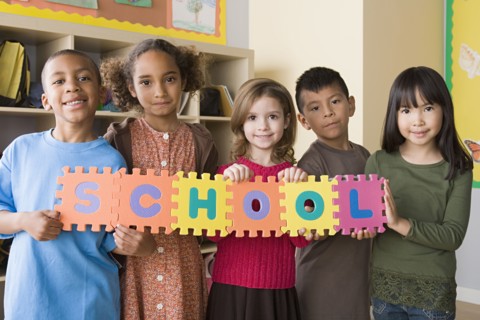 Portrait of schoolchildren (6-7) holding colorful letters. Photo: Rob Lewine