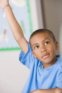 Schoolboy (6-7) raising hand. Photo : Rob Lewine