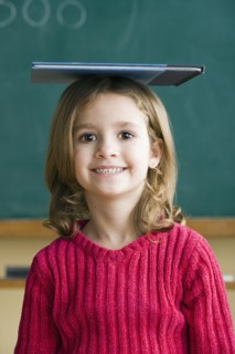 Portrait of girl (6-7) balancing book on head. Photo : Rob Lewine