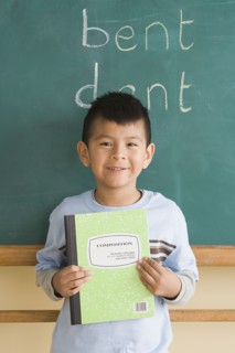 Smiling boy (6-7) showing notebook in classroom. Photo: Rob Lewine