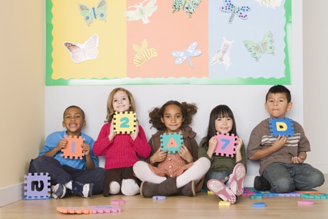 Children (6-7) sitting and holding letters in classroom. Photo : Rob Lewine
