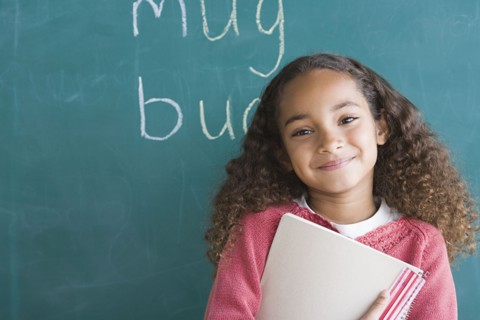 Smiling girl (6-7) against blackboard. Photo : Rob Lewine
