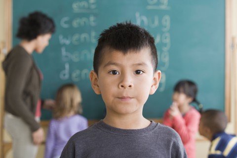 Portrait of boy (6-7) with schoolmates in background. Photo : Rob Lewine