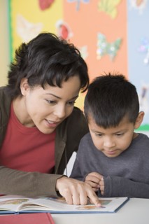 Teacher helping boy (6-7) to read. Photo: Rob Lewine