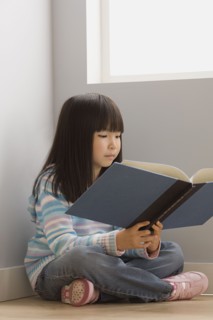 Girl (6-7) reading book in classroom. Photo : Rob Lewine