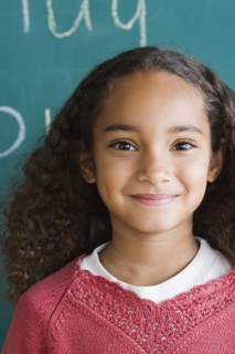 Portrait of schoolgirl (6-7) against blackboard. Photo : Rob Lewine