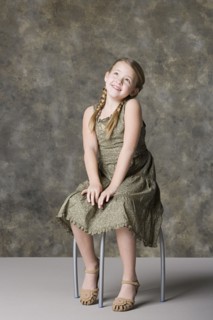 Portrait of smiling girl (8-9) sitting on stool. Photo : Rob Lewine