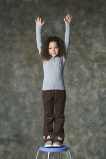 Portrait of smiling girl (8-9) with arms raised, studio shot. Photo : Rob Lewine