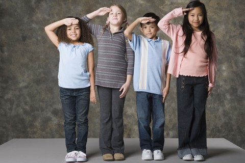 Children (6-7, 8-9) saluting, studio shot. Photo : Rob Lewine