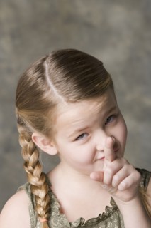 Portrait of smiling girl (8-9) pointing to camera, studio shot. Photo : Rob Lewine