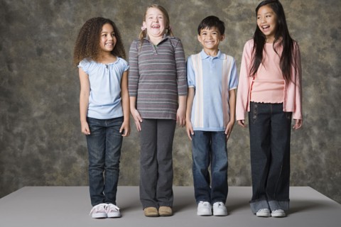 Children (8-9) laughing together, studio shot. Photo : Rob Lewine