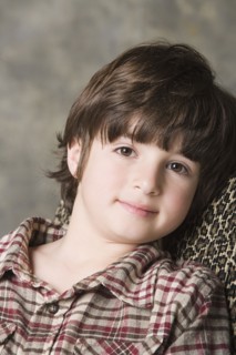 Portrait of smiling (6-7) boy, studio shot. Photo : Rob Lewine