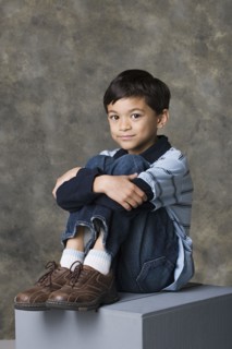 Smiling boy (8-9) standing, studio shot. Photo : Rob Lewine