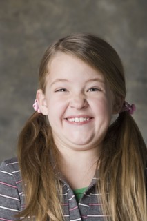 Portrait of smiling girl (8-9), studio shot. Photo: Rob Lewine