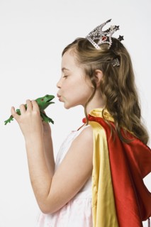 Girl (8-9) dressed as princess kissing frog, studio shot. Photo: Rob Lewine