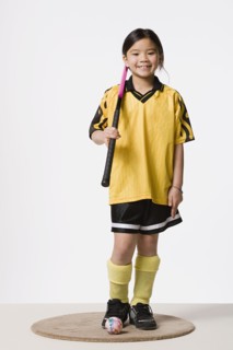 Portrait of smiling girl (8-9) wearing field hockey costume, studio shot. Photo : Rob Lewine