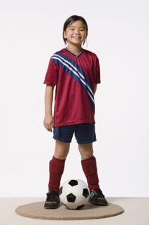 Smiling girl (8-9) wearing soccer uniform, studio shot. Photo : Rob Lewine