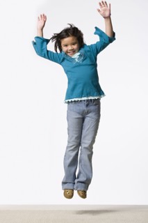 Studio shot of smiling girl (8-9) jumping. Photo : Rob Lewine