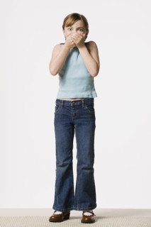 Smiling girl (8-9) covering her mouth, studio shot. Photo : Rob Lewine