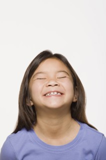 Portrait of smiling girl (8-9) with eyes closed, studio shot. Photo : Rob Lewine