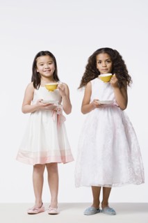 Two girls (8-9) wearing dresses and drinking tea, studio shot. Photo : Rob Lewine