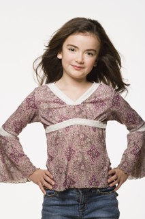 Portrait of girl (8-9) with hands on hips, studio shot. Photo : Rob Lewine