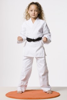 Studio portrait of smiling girl (8-9) wearing gi. Photo : Rob Lewine