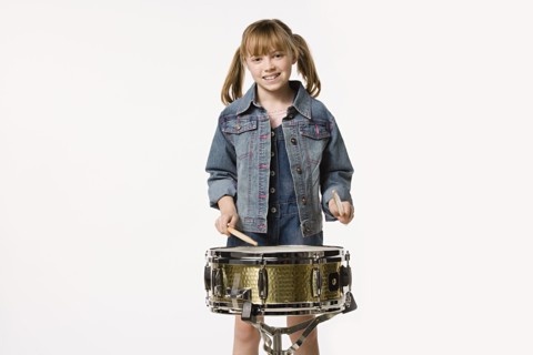 Studio portrait of girl (8-9) playing drums. Photo: Rob Lewine