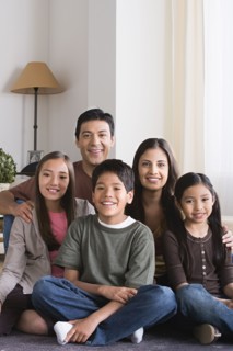 Portrait of happy family with three children (8-9, 10-11) sitting on floor. Photo : Rob Lewine