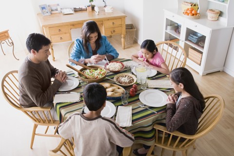 Family with three children (8-9, 10-11) praying at table before dining. Photo : Rob Lewine