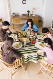 Family with three children (8-9, 10-11) praying at table before dining. Photo : Rob Lewine
