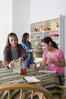 Mother with two daughters (8-9, 10-11) cleaning from table. Photo : Rob Lewine